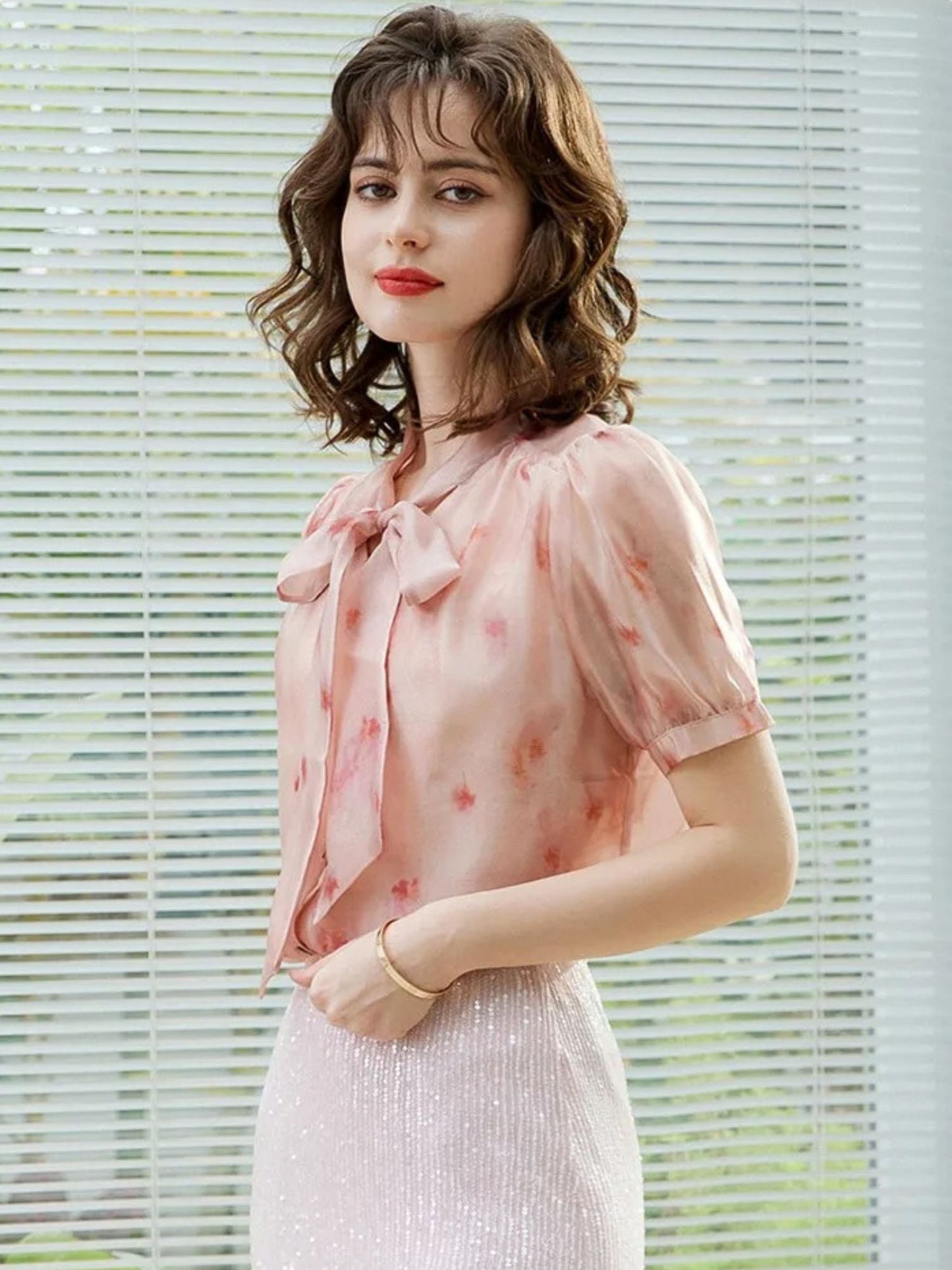 Frontalansicht der Frau in rosa Bluse mit Schleife und weißem Rock.