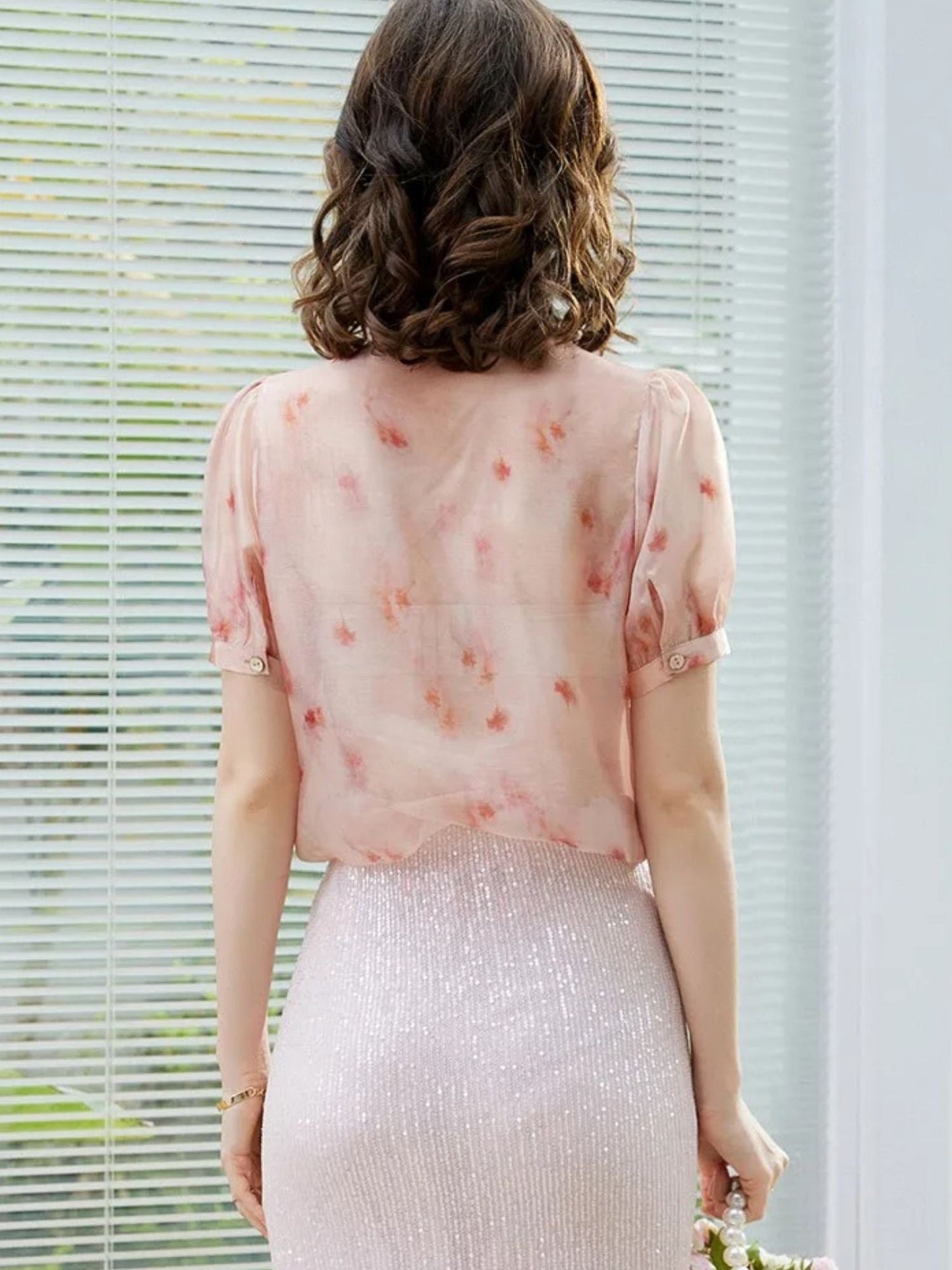 Rückansicht in rosa Bluse mit Schleife und weißem Rock.