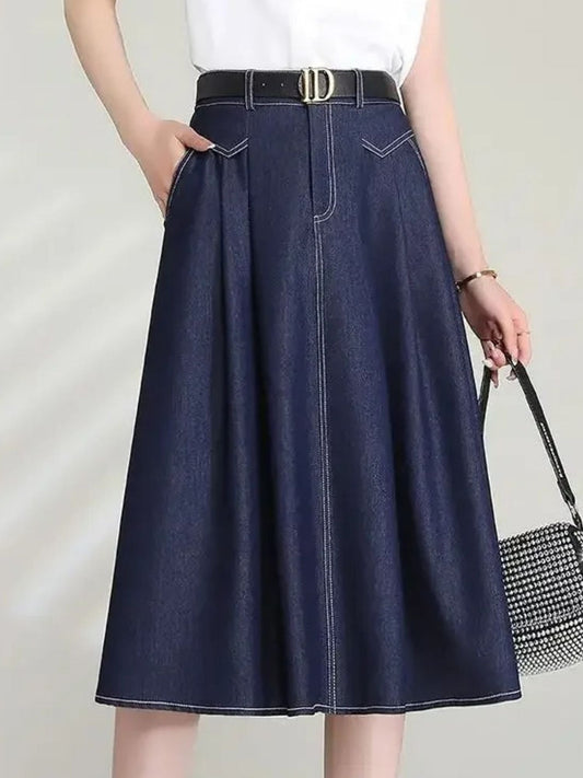 Frau trägt dunkelblauen Jeans-Midirock mit Gürtel und Handtasche.