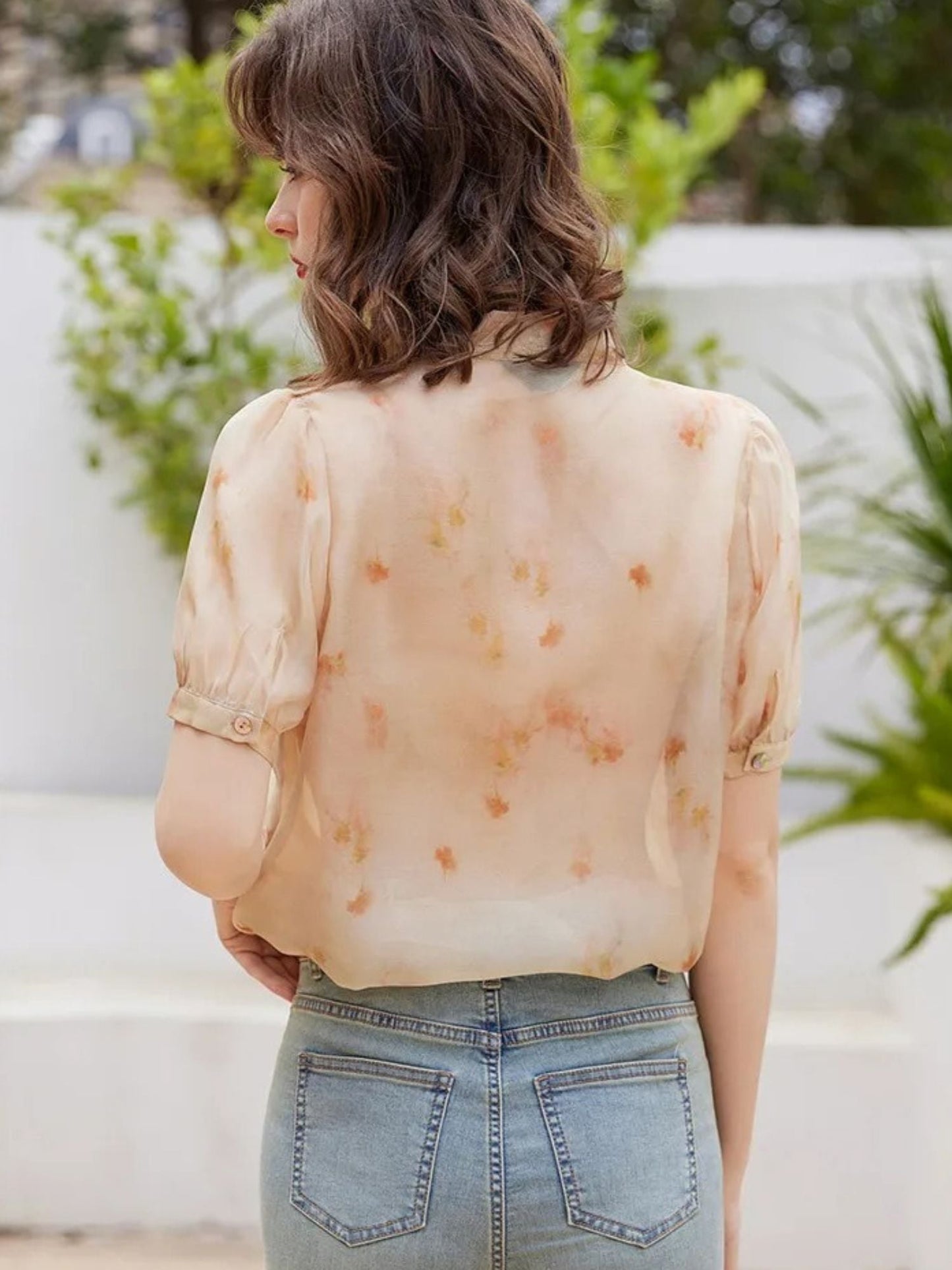 Rückansicht der pfirsichfarbenen Bluse mit Jeans.
