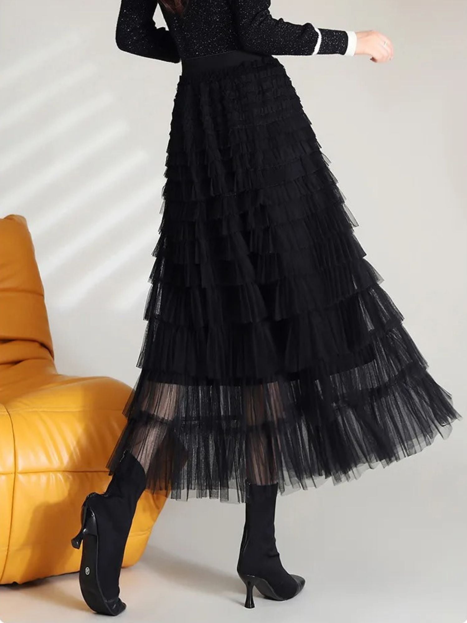 Seitenansicht des schwarzen Stufenrocks mit schwarzen Stiefeletten.