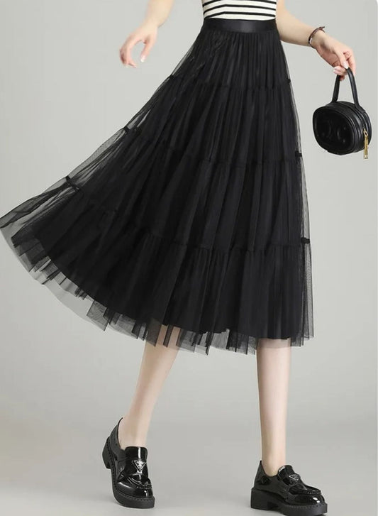 Frau trägt schwarzen Tüll-Midirock mit gestreiftem Oberteil und Handtasche.